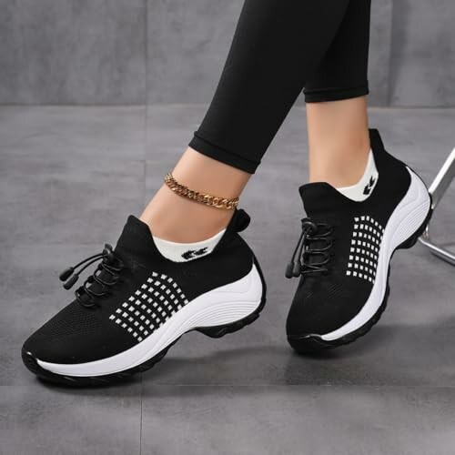 Schwarze und weiße Sneakers an Füßen mit Leggings