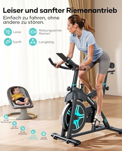 Frau auf Heimtrainer neben Baby in Babyschale